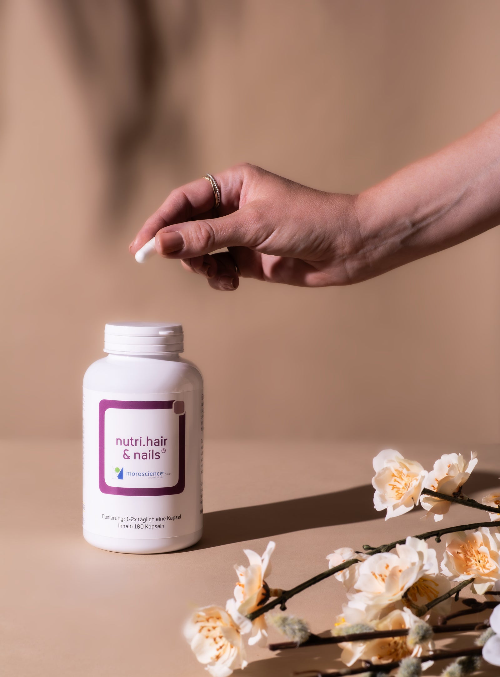 Model hält nutri hair and nails kapsel erdton